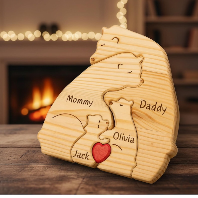 Puede incluir: Rompecabezas familiar de osos de madera con las palabras "Mommy", "Daddy", "Olivia" y "Jack" grabadas. Un coraz&oacute;n rojo est&aacute; en el centro. El rompecabezas es de madera clara.
