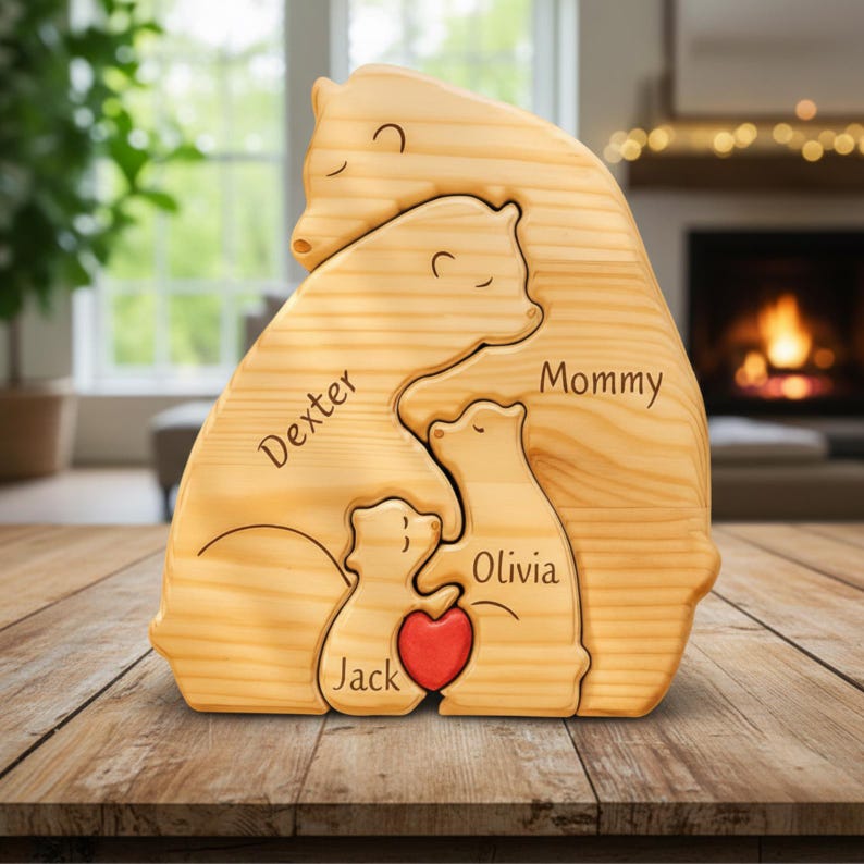 Puede incluir: Rompecabezas familiar de osos de madera con los nombres "Dexter", "Mommy", "Olivia" y "Jack" grabados. Un coraz&oacute;n rojo en el centro. Hecho de madera clara.