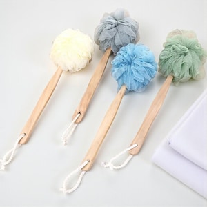 May include: Five bath brushes with wooden handles and colorful mesh scrubbers. The scrubbers are in shades of yellow, gray, blue, and green. Each brush has a white rope loop for hanging.