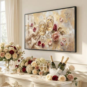 May include: A framed artwork depicts two champagne glasses, rings, and roses. A table displays champagne bottles in an ice bucket, more glasses, and floral arrangements with red and cream roses. The scene evokes celebration.