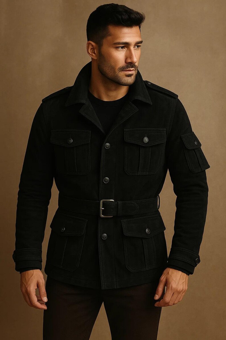 May include: Black suede jacket with multiple pockets, a belt, and a button-up front. The jacket has a classic collar and epaulettes on the shoulders. The model is wearing a black shirt underneath.
