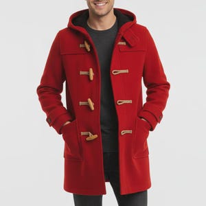 May include: A red duffel coat with a hood and wooden toggle closures. The coat has two front pockets and a black lining in the hood. The person is wearing a gray shirt underneath.