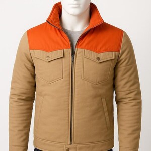 May include: A tan and orange jacket with a zip-up front, two chest pockets, and a collared neckline. The jacket has a quilted design and is displayed on a mannequin. The jacket is a neutral color and is suitable for various outfits.