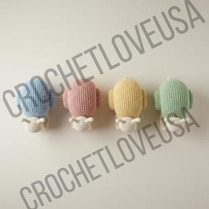 Könnte beinhalten: Vier gehäkelte Kaktus-Ornamente in Pastellfarben: Hellblau, Rosa, Gelb und Grün. Jeder Kaktus hat eine weiße gehäkelte Basis und ein kleines weißes Detail oben. Der Text "CROCHETLOVEUSA" ist im Bild als Wasserzeichen zu sehen.