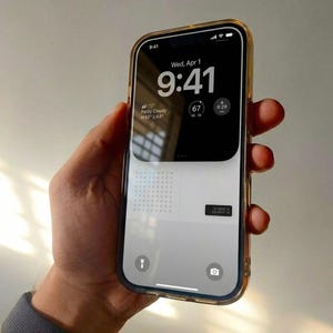 May include: A smartphone with a clear case is held in a hand. The screen displays the time as 9:41 AM, the date, and weather information. The phone has a gold-colored border.