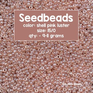 Pode incluir: Um close-up de um monte de pequenas contas redondas de cor rosa nacarada. As contas são de tamanho 15/0 e pesam aproximadamente 9-11 gramas. O texto "Seedbeads" está escrito em letras grandes brancas na parte superior da imagem. O texto "color: shell pink luster", "size: 15/0" e "qty: ~ 9-11 grams" está escrito em letras brancas abaixo da palavra "Seedbeads". O texto "Avalon Beads" está escrito em letras pequenas brancas na parte inferior da imagem.