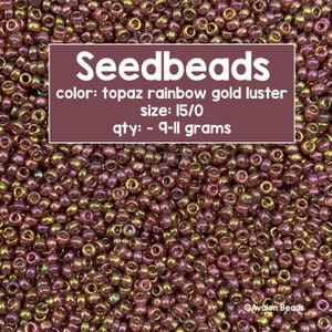 Pode incluir: Close-up de contas de sementes em brilho dourado arco-íris topázio. As contas são do tamanho 15/0 e a quantidade é de aproximadamente 9-11 gramas. O texto "Seedbeads" está incluído.