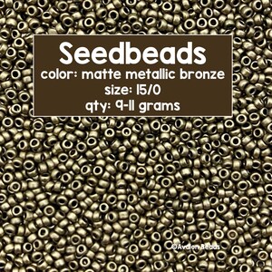 May include: A close-up image of a pile of matte metallic bronze seed beads. The beads are size 15/0 and weigh 9-11 grams. The text "Seedbeads" is written in white on a brown background. The text "color: matte metallic bronze" is written in white on a brown background. The text "size: 15/0" is written in white on a brown background. The text "qty: 9-11 grams" is written in white on a brown background.