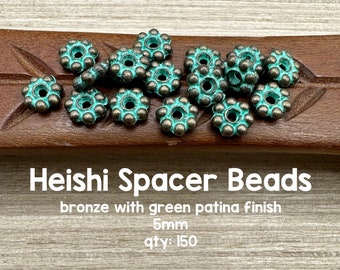May include: Heishi spacer beads in bronze with a green patina finish. The beads are 5mm in size and have a floral design. The image shows a collection of these beads, perfect for jewelry making.