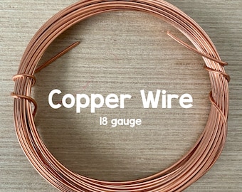 May include: A coil of copper wire, 18 gauge, on a wooden surface. The wire is a warm copper color. The text "Copper Wire 18 gauge" is printed on the image.
