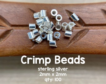 May include: A pile of 100 silver crimp beads, 2mm x 2mm in size, for jewelry making. The beads are on a wooden surface. Crimp Beads sterling silver 2mm x 2mm qty: 100 ©Avalon Beads