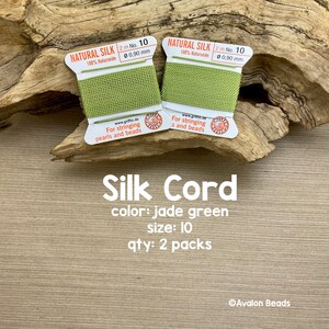 May include: Two spools of jade green silk cord, each 2 meters long and 0.90 mm thick. The spools are labeled "Natural Silk 100% Naturseide" and "For stringing pearls and beads".