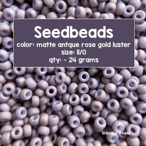 Pode incluir: Close-up de um monte de contas de semente de cor rosa antigo fosco com brilho dourado. As contas são de tamanho II/O e pesam aproximadamente 24 gramas. Contas de semente, cor: rosa antigo fosco com brilho dourado, tamanho: II/O, quantidade: ~ 24 gramas.