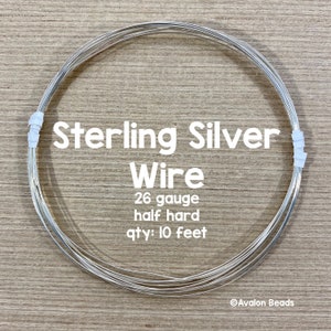 May include: A coil of sterling silver wire, 26 gauge, half hard, with the text "Sterling Silver Wire". The wire is held together with white tape. The quantity is 10 feet.
