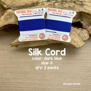 May include: Two spools of dark blue silk cord, each 2 meters long and 0.70 mm thick. The spools are labeled "Natural Silk 100% Naturseide" and "For stringing pearls and beads".