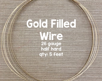 May include: Gold filled wire, 26 gauge, half hard, 5 feet long. The wire is coiled in a circle on a wooden surface.  ©Avalon Beads