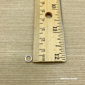 May include: A silver jump ring measuring approximately 6 mm in diameter, next to a ruler.