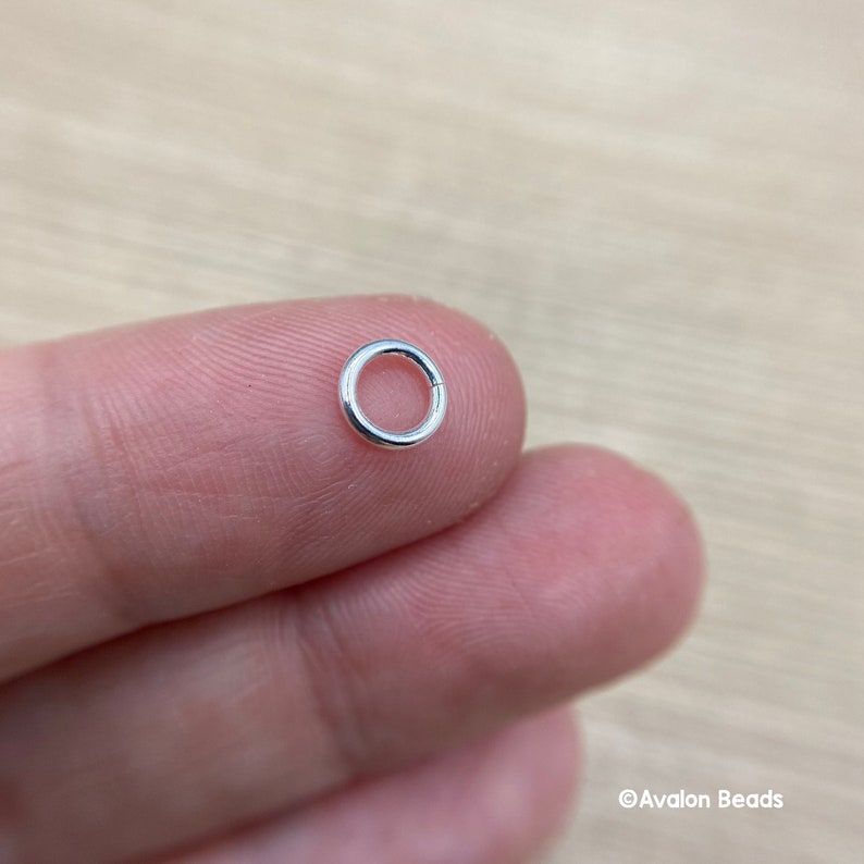May include: A silver jump ring, a small metal ring used for connecting jewelry components.