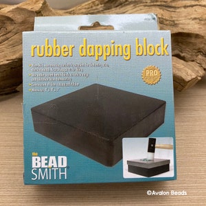 May include: A black rubber dapping block in a box. The box reads "rubber dapping block" and "the BEAD SMITH". The block measures 10.16cm x 10.16cm x 2.54cm and is for flattening wire and chasing metal.