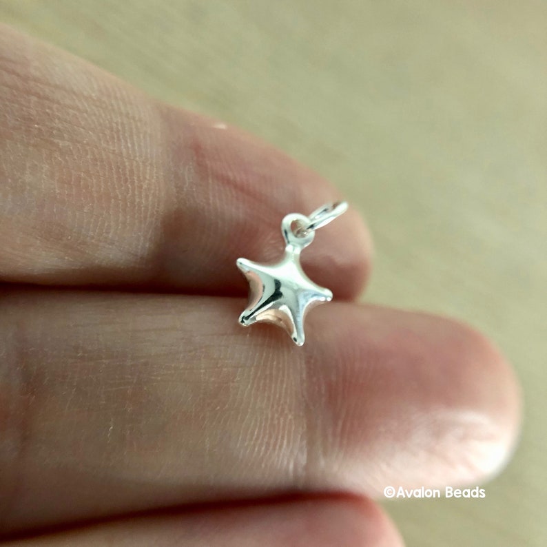 May include: A silver star charm with a loop for attaching to a necklace or bracelet.