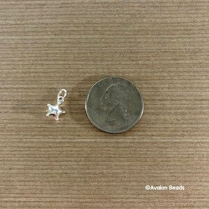 May include: A silver star charm, approximately the size of a US quarter, for jewelry making.