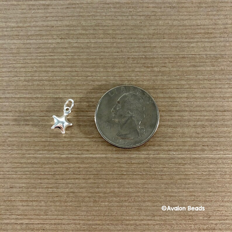May include: A silver star charm, approximately the size of a US quarter, for jewelry making.