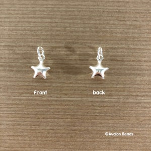 May include: Silver star charm with a smooth, shiny finish. The charm is shown from the front and back.