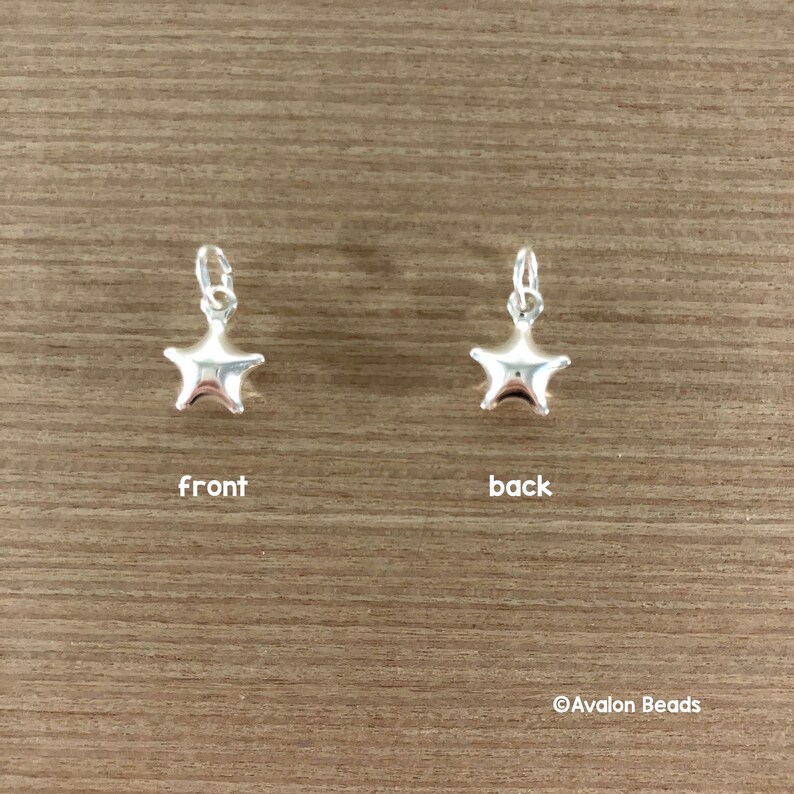 May include: Silver star charm with a smooth, shiny finish. The charm is shown from the front and back.