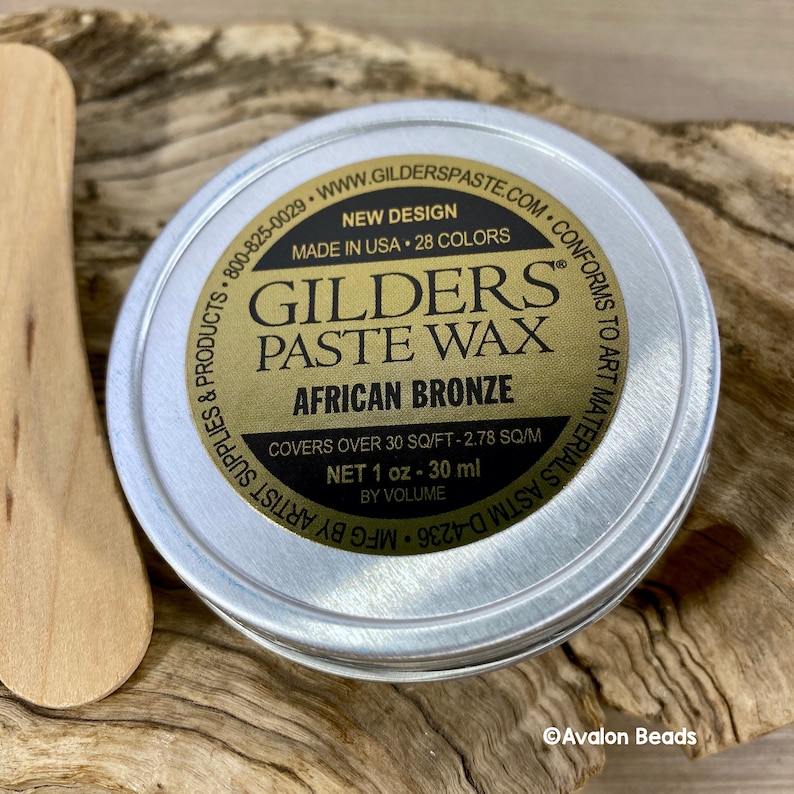 Pode incluir: Uma lata redonda de metal com um r&oacute;tulo dourado que diz "GILDERS PASTE WAX AFRICAN BRONZE". O r&oacute;tulo tamb&eacute;m diz "Novo design, Feito nos EUA, 28 cores, Cobre mais de 30 p&eacute;s quadrados - 2,78 metros quadrados, Conte&uacute;do l&iacute;quido 1 oz - 30 ml por volume".