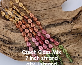 Puede incluir: Hebras de cuentas de vidrio checo con forma de hoja, en tonos dorados, cobrizos, rosas y verdes. Cada hebra mide aproximadamente 17,78 cm de largo. Las cuentas se muestran sobre un trozo de madera envejecida.