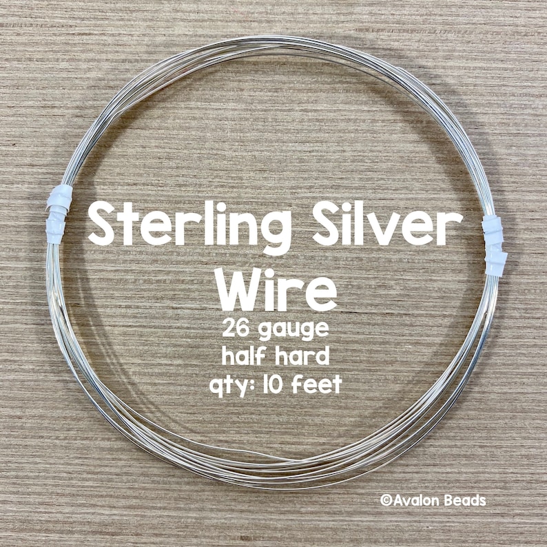 May include: A coil of sterling silver wire, 26 gauge, half hard, with the text "Sterling Silver Wire". The wire is held together with white tape. The quantity is 10 feet.