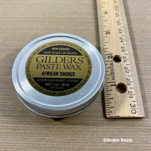 Pode incluir: Uma lata prateada de Gilder's Paste Wax na cor bronze africano. A lata &eacute; etiquetada com o nome do produto, a cor e as instru&ccedil;&otilde;es de uso. Ela cobre 30 p&eacute;s quadrados e cont&eacute;m 1 on&ccedil;a (30 ml) de cera.