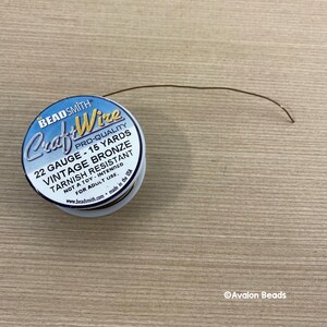 May include: A spool of 22 gauge vintage bronze craft wire, tarnish resistant, with 15 yards of wire. The spool is labeled "Beadsmith Craft Wire Pro-Quality".