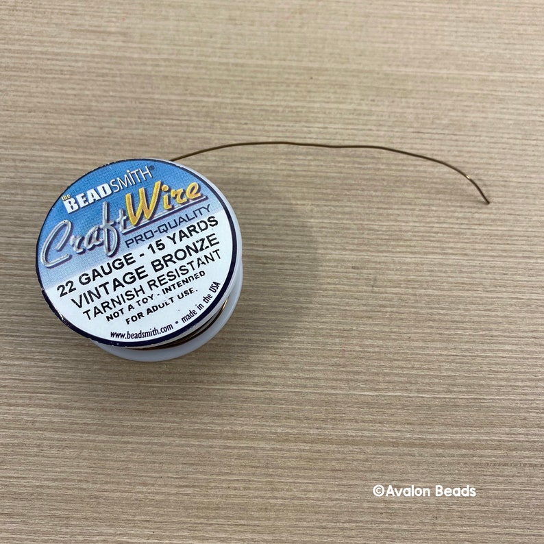 May include: A spool of 22 gauge vintage bronze craft wire, tarnish resistant, with 15 yards of wire. The spool is labeled "Beadsmith Craft Wire Pro-Quality".