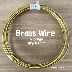 May include: A coil of 12 gauge brass wire, 5 feet long. The wire is coiled and tied with a white ribbon. The text "Brass Wire" is printed in white on a wooden background. The text "12 gauge" and "qty: 5 feet" is printed in white below the text "Brass Wire". The text "©Avalon Beads" is printed in white in the bottom right corner of the image.
