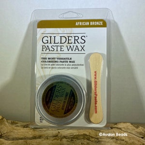Pode incluir: Uma pequena lata de Cera em Pasta Gilders na cor Bronze Africano. A lata &eacute; de prata com um r&oacute;tulo preto e texto branco. O r&oacute;tulo inclui o nome da marca, o nome do produto, a cor e o peso l&iacute;quido. A lata &eacute; embalada com um aplicador de madeira. A embalagem &eacute; de pl&aacute;stico transparente com um fundo dourado e o nome da marca e o nome do produto em texto preto.