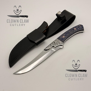 May include: A silver and black knife with a decorative handle and a black leather sheath. The knife has a curved blade and ornate detailing. The text "CLOWN CLAW CUTLERY" is printed on the image.
