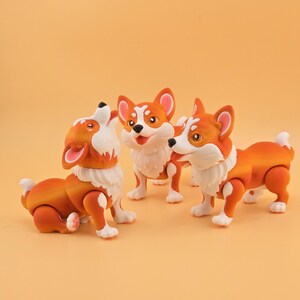 Pu&ograve; includere: Tre statuette di cani corgi arancioni e bianchi. Uno sta ululando, un altro &egrave; in piedi e il terzo &egrave; in posizione di camminata. Le statuette hanno pelliccia bianca intorno al collo e sulle zampe, con orecchie arancioni.