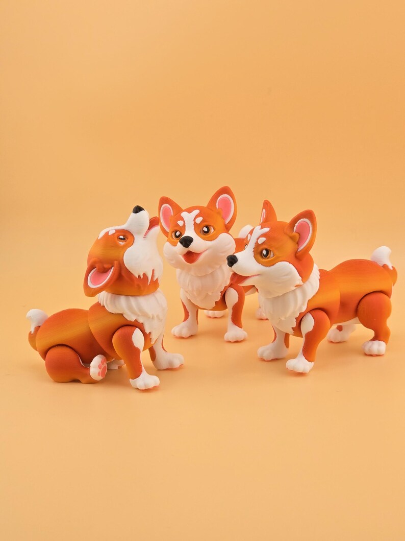 Pu&ograve; includere: Tre statuette di cani corgi arancioni e bianchi. Uno sta ululando, un altro &egrave; in piedi e il terzo &egrave; in posizione di camminata. Le statuette hanno pelliccia bianca intorno al collo e sulle zampe, con orecchie arancioni.