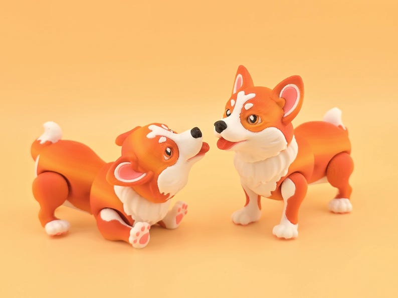 Pu&ograve; includere: Due statuette di corgi arancioni e bianchi. Uno &egrave; sdraiato, che guarda l'altro, in piedi. I corgi hanno petto, zampe e punte della coda bianche. Lo sfondo &egrave; di un arancione chiaro uniforme.
