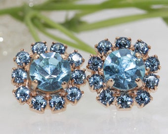 May include: A pair of blue crystal earrings with a gold setting. The earrings are round and have a cluster of smaller crystals surrounding a larger centre crystal.