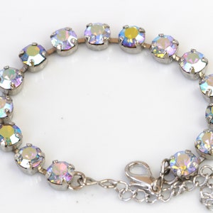 May include: A silver chain bracelet with iridescent round crystals. The bracelet has a lobster clasp closure.
