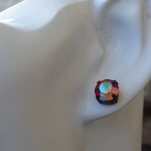 May include: A pair of small, round, red iridescent earrings with black metal settings.