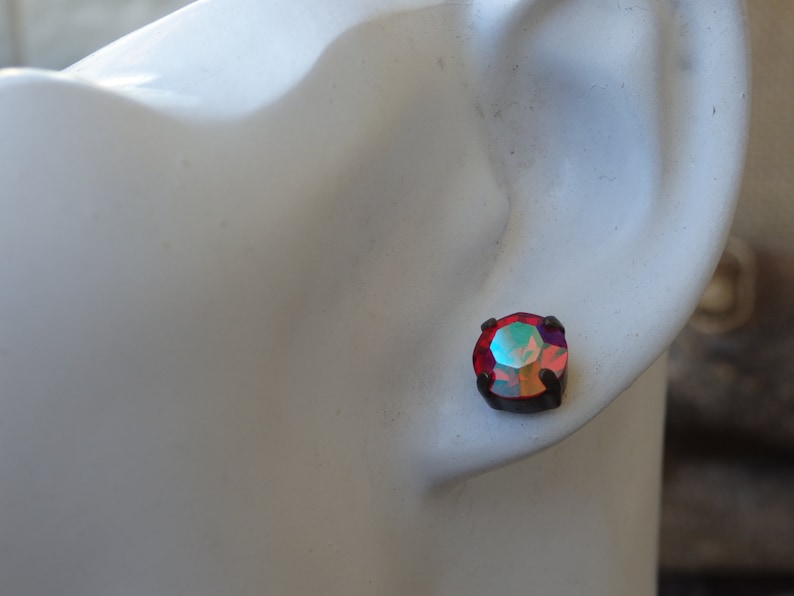 May include: A pair of small, round, red iridescent earrings with black metal settings.