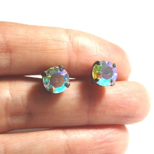 May include: A pair of iridescent round stud earrings with a black metal setting.