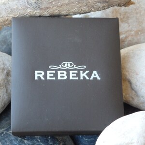 May include: A dark brown box with the word "REBEKA" printed in white on the front.