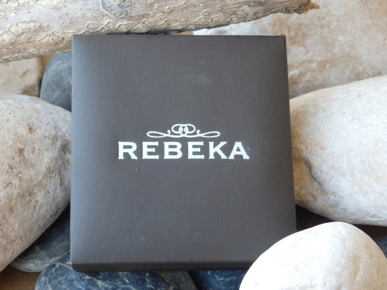 May include: A dark brown box with the word "REBEKA" printed in white on the front.