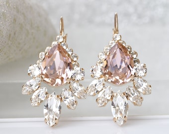 Puede incluir: Un par de pendientes de oro con un cristal rosa pálido en forma de lágrima rodeado de cristales transparentes más pequeños.