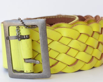 May include: A bright yellow braided leather belt with a silver buckle. The buckle has a small chain attached to it.