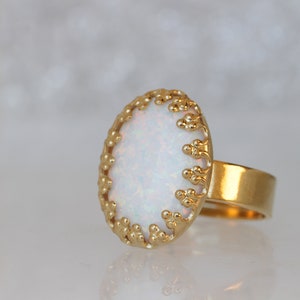 May include: A gold ring with a white opal stone set in a delicate, beaded design.